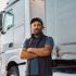 Confident truck driver standing outdoors with arms crossed and looking at camera. Copy space.